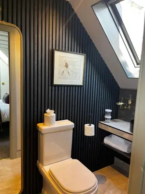 a bathroom with a toilet and a black wall at Abbotsford Hotel in Ayr