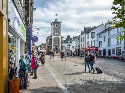 a group of people walking down a street with a clock tower at 1 Bed in Keswick SZ468 in Keswick