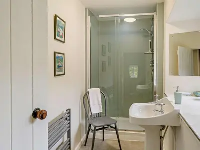 a bathroom with a shower and a sink and a chair at 4 Bed in Holmrook oc-sz158 in Eskdale