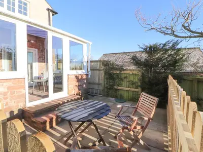 a patio with a table and chairs on a deck at Hillside Hideaway in Wigton
