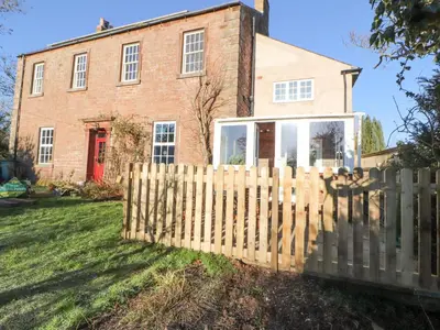 a wooden fence in front of a brick house at Hillside Hideaway in Wigton