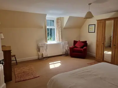 a bedroom with a bed and a red chair at The Coach House - Bargany in Girvan