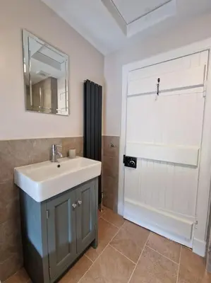 a bathroom with a sink and a door with a mirror at The Coach House - Bargany in Girvan