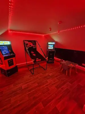 a room with two arcade games and a red wall at HollyJess Hoose in Stranraer