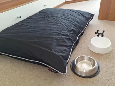 a black pillow on the floor next to a dog bowl at Inglenook Lodge in Lamplugh