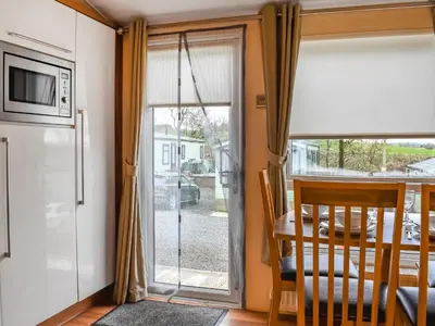 a kitchen with a sliding glass door to a dining room at Inglenook Lodge in Lamplugh