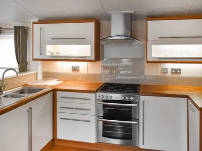 a kitchen with white cabinets and a stove top oven at Inglenook Lodge in Lamplugh