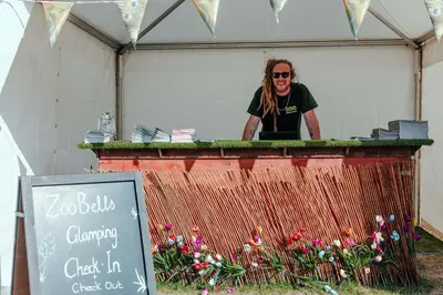 a man standing behind a table with flowers at Duke Travel Official TT Glamping - Douglas in Kirk Braddon