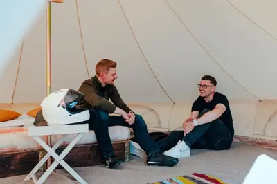 two men sitting on a bed in a tent at Duke Travel Official TT Glamping - Douglas in Kirk Braddon