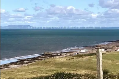 a view of the ocean with a city in the distance at ERIN NEAMH - Magnificent sea views cosy cottage in Cumbria in Harrington