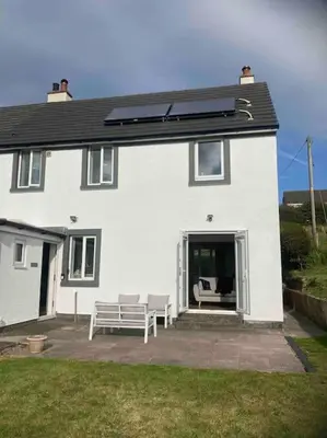 a white house with a bench in front of it at ERIN NEAMH - Magnificent sea views cosy cottage in Cumbria in Harrington