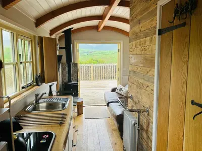 a kitchen with a sink and a couch in a room at Shepherds Hut at Maes Uldale stunning fell views and next door to popular cafe for sweet treats in Uldale
