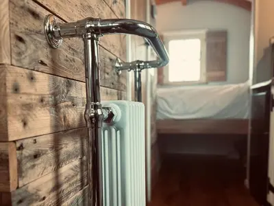 a bathroom with a water hose attached to a wall at Shepherds Hut at Maes Uldale stunning fell views and next door to popular cafe for sweet treats in Uldale