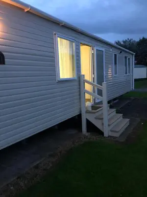 a mobile home with a porch and stairs on it at Lovely Caravan in Turnberry