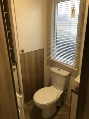 a small bathroom with a toilet and a window at Lovely Caravan in Turnberry