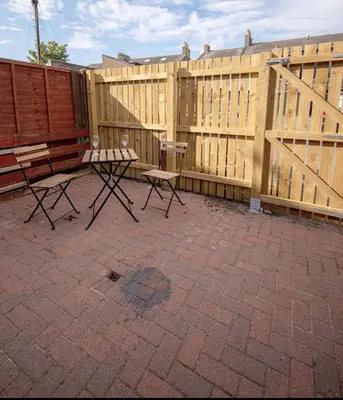 a wooden fence with two benches and a table at The Bradan - Troon - Coorie Doon Stays in Troon