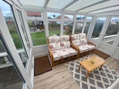 a screened in porch with a couch and a table at 17 The Park in Onchan