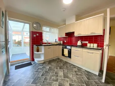 a kitchen with red walls and a red tile floor at 17 The Park in Onchan