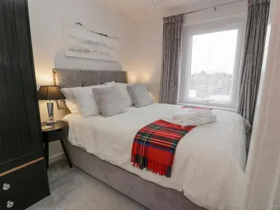 a bedroom with a large bed with a window at Rosalin Cottage in Irvine