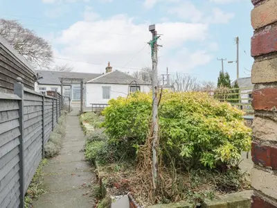 a path in a yard next to a fence at Rosalin Cottage in Irvine