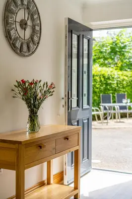 a vase of flowers on a wooden table in front of a door at Acorn Apartment 1 in Keswick
