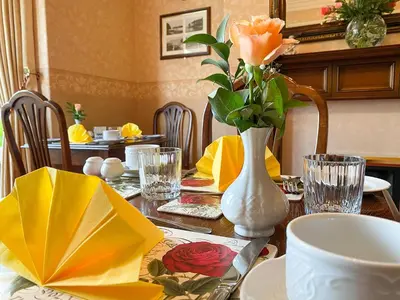 a dining room table with a vase with roses in it at Number 10 Bed & Breakfast in Keswick