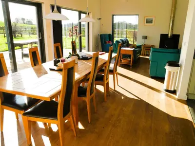 a dining room with a wooden table and chairs at The Longhouse in Castle Douglas