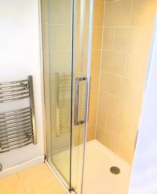 a shower with a glass door in a bathroom at The Longhouse in Castle Douglas