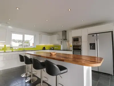 a kitchen with white cabinets and a wooden counter top at Merse End in Dalbeattie