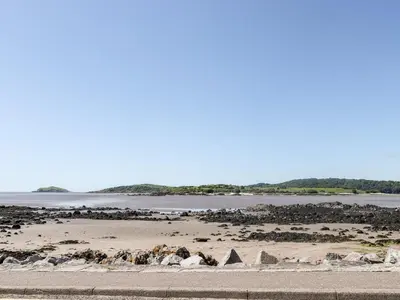 a beach with rocks and a body of water at Merse End in Dalbeattie