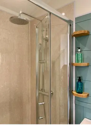 a shower with a glass door in a bathroom at The Mad Hatter's Shepherd's Hut in Carlisle