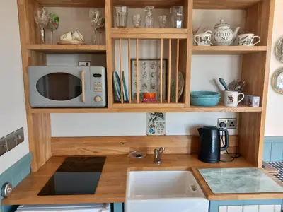 a kitchen counter with a microwave and a sink at The Mad Hatter's Shepherd's Hut in Carlisle
