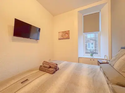 a bedroom with a bed with a flat screen tv on the wall at Barassie, Troon in Troon