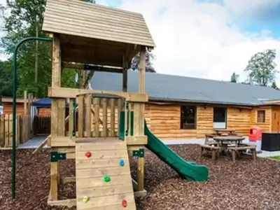 a playground with a wooden house and a slide at Beautiful Cosy Holiday Home in Gorgeous Location - Pass the Keys in Beattock