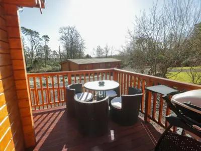 a wooden deck with a table and chairs on it at Little Lodge in Newton Stewart
