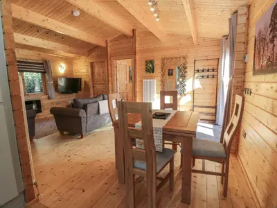 a dining room and living room in a log cabin at Little Lodge in Newton Stewart