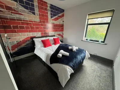 a bedroom with a bed with red pillows and a brick wall at Quayside Apartment -2 Bedrooms - Sleeps 4 in Whitehaven