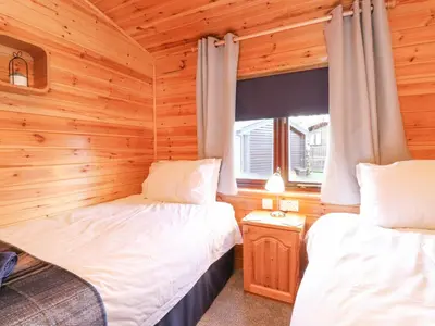 two beds in a room with wooden walls at Hayeswater Lodge in Keswick