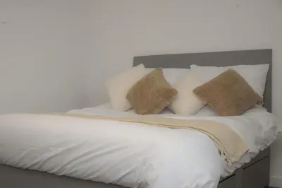 a bed with white sheets and pillows on it at Dumfries Apartment 2 in Dumfries