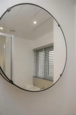 a round mirror on a white wall with a window at Dumfries Apartment 2 in Dumfries