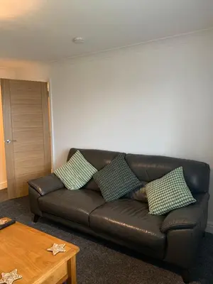 a brown leather couch in a living room with a table at Dumfries Apartment 2 in Dumfries