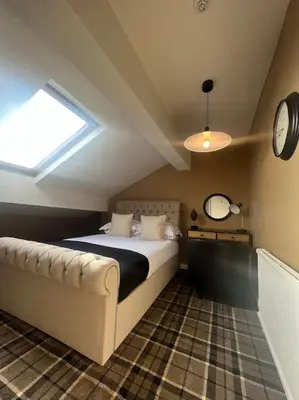 a bedroom with a bed and a clock on the wall at Tynwald Apartments in Douglas