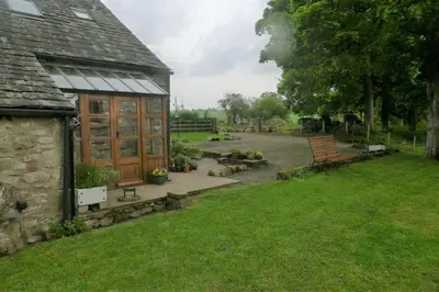 a garden with a building and a bench and a park at North Lake District rural retreat in Penrith