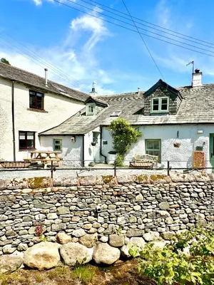 a stone wall in front of a building at Cottage On The Brook in Braithwaite