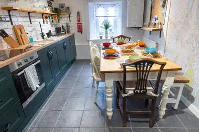 a kitchen with a table and chairs and a kitchen with green cabinets at Cottage On The Brook in Braithwaite