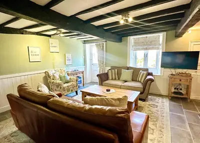 a living room with two couches and a table at Cottage On The Brook in Braithwaite