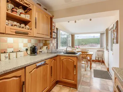 a kitchen with wooden cabinets and a table at 3 Bed in Portinscale 93949 in Portinscale
