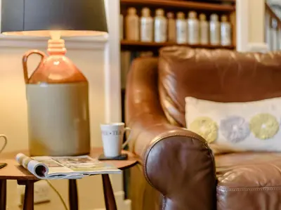 a leather chair and a lamp on a side table with a coffee cup at 3 Bed in Portinscale 93949 in Portinscale
