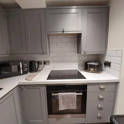 a kitchen with gray cabinets and a stove top oven at Kirkcudbright Holiday Apartments - Apartment A in Kirkcudbright