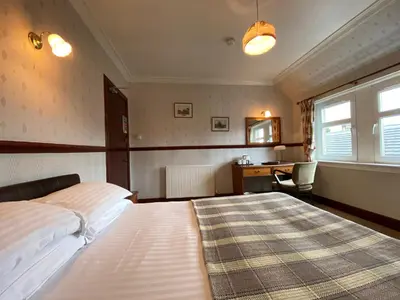 a bedroom with a large bed and a desk at Kings Arms Hotel in Lockerbie